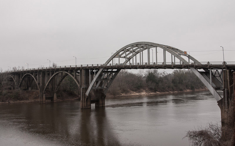 The arches of the Edmund Pettus Bridge seen from the east bank, a few hundred yards downstream.