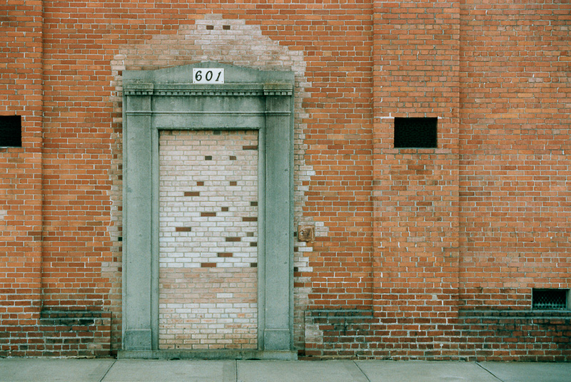 photo of a brick wall with a doorway that has been filled in with more bricks